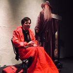 Chris Neville-Smith is Kevin, setting in a red sleeping bag with a Gandalf cardboard cut-out behind